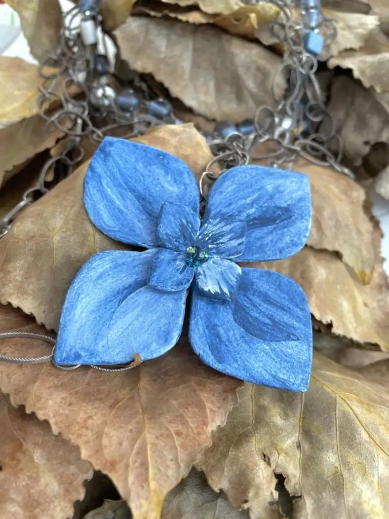Collier multirangs de chaînes et perles, motif central : fleur d’hortensia en papier mâché teinté en bleu